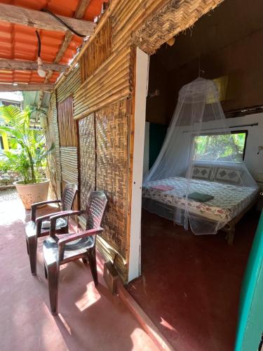 um quarto com uma cama e duas cadeiras em Hobknob, Goa - hostel with a pool em Nogorcem