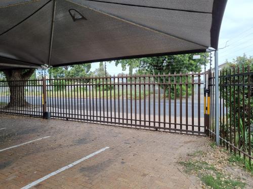 a black fence with a canopy over a parking lot at Old Oak Guest House in Bellville