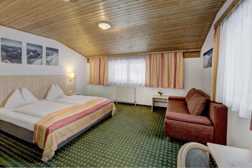 een hotelkamer met een bed en een stoel bij Hotel-Restaurant Bike&Snow Lederer in Mühlbach am Hochkönig