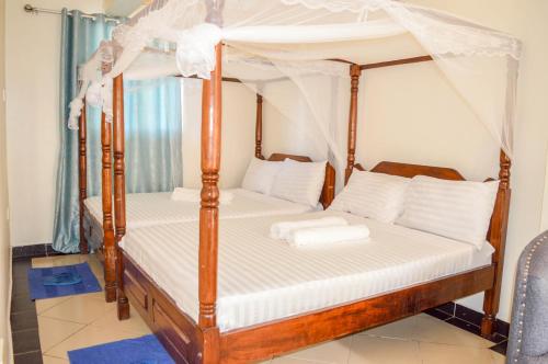 Roma Stays - Cozy 3 Bedroom Apartment with Swimming Pool in Shanzu في مومباسا: غرفة نوم بسريرين مظلة مع ملاءات بيضاء