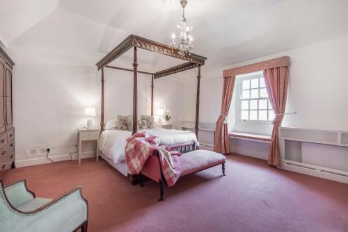 ein Schlafzimmer mit einem Himmelbett und einem Stuhl in der Unterkunft Emmetts Grange House in Minehead
