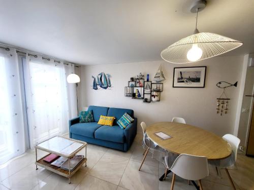un salon avec un canapé bleu et une table dans l'établissement Appartement Moderne au Centre-Ville, 150m Plage, WiFi, Confort Idéal pour Familles - FR-1-92-876, à Les Sables-dʼOlonne