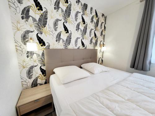 - une chambre avec un lit et un mur recouvert de papier peint dans l'établissement Appartement Moderne au Centre-Ville, 150m Plage, WiFi, Confort Idéal pour Familles - FR-1-92-876, à Les Sables-dʼOlonne
