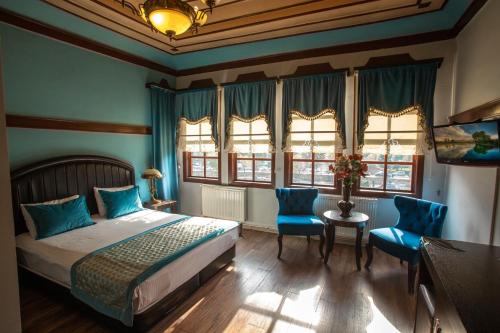 a bedroom with a bed and two blue chairs at EMİN EFENDİ KONAKLARI in Amasya