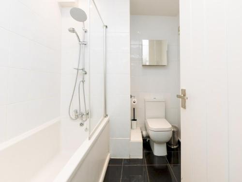 a white bathroom with a toilet and a shower at Delightful retreat in Larkhall with free parking - Pass the Keys in Bath