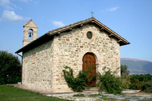 a small brick church with a door and a steeple at Valle di Assisi Country Apartments in Assisi