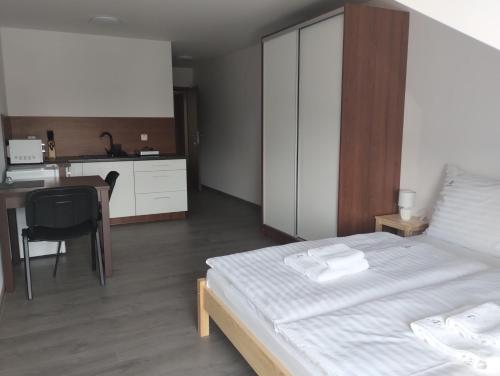 a bedroom with a bed and a desk and a kitchen at Apartmány Adam in Liptovská Teplá