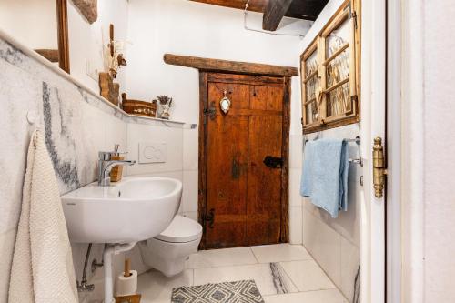 a bathroom with a toilet and a wooden door at Historisches Apartment Duregghof in San Genesio Atesino