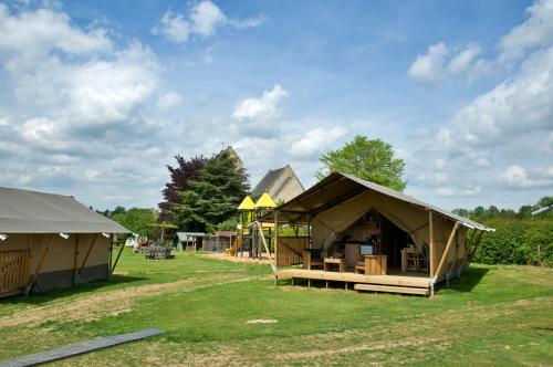 a group of tents in a field with a playground at Camping La Dolce Vita in Ransdaal