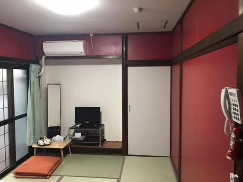 a room with red walls and a room with a living room at Yamamoto Ryokan in Fukuoka