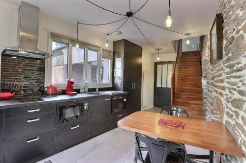 - une cuisine avec une table en bois et un mur en pierre dans l'établissement Garden Hotel Rennes Centre Gare, à Rennes