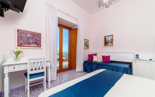a bedroom with a bed and a desk and a window at Hotel La Bussola in Amalfi