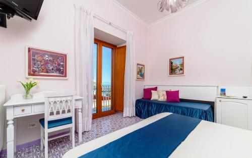 um quarto com uma cama, uma secretária e uma janela em Hotel La Bussola em Amalfi