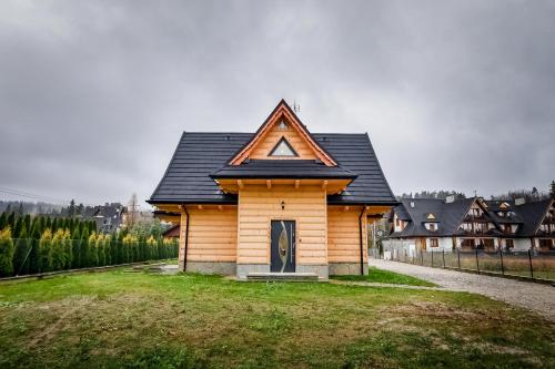 a small wooden house with a triangular roof at Magiczny Domek in Białka Tatrzanska