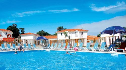 - une piscine avec des chaises et des personnes dans l'eau dans l'établissement 400m de la plage des Sables d'Or - Maison pour 8, à Saint-Brévin-les-Pins