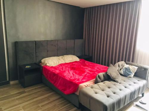 a bedroom with a bed with a red blanket and a couch at مجمع الجاردنز افينيو in Amman
