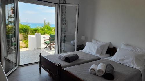 two beds in a bedroom with a view of the ocean at Beachfront Oleanders House in Skala in Skala Kefalonias