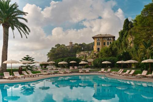 a pool with chairs and umbrellas and a building at Grand Hotel Miramare in Santa Margherita Ligure