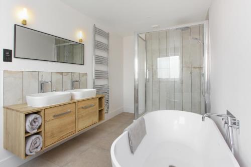 Un baño con bañera, lavabo y espejo. en SandiBay, en Sandwich