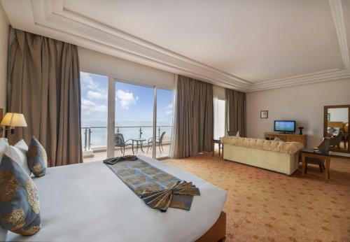 タンジェにあるグランド モガドール シー ビュー ＆ スパのベッドと大きな窓が備わるホテルルームです。
