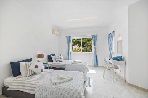 two beds in a white room with a window at Villa Amoreira by Villa Plus in Lagoa