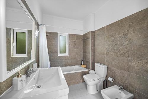 a bathroom with a tub and a toilet and a sink at Villa Amoreira by Villa Plus in Lagoa
