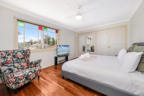 a bedroom with a bed and a chair and a television at Eastwood Central, Walk to Station & Shops, Drive to Olympic in Sydney