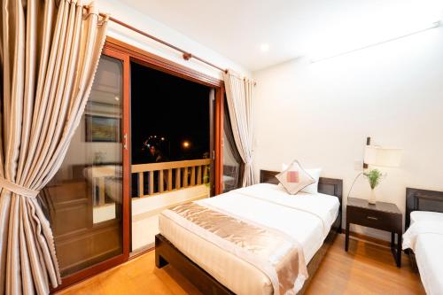 a bedroom with a bed and a large window at B'Lan Riverside Villa in Hoi An