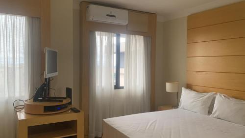 a bedroom with a bed and a tv and a window at Quarto em hotel pertinho do Aeroporto de Congonhas - H2208 in São Paulo