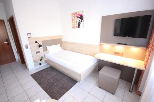 Habitación pequeña con cama y TV de pantalla plana. en Appartements Biedermeier, en Bad Krozingen