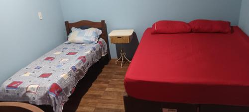 een slaapkamer met 2 bedden met rode lakens en een tafel bij Aconchego Santa Luzia in Pirenópolis