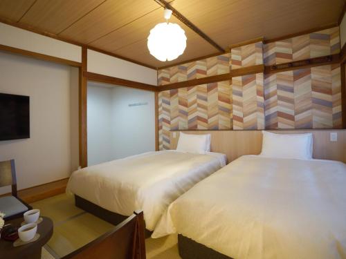 Habitación de hotel con 2 camas y TV en Hotel New Gaea Iizuka, en Iizuka