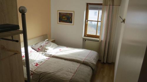 uma cama num quarto com uma janela em Ferienwohnung Chiemseestrand em Arlaching