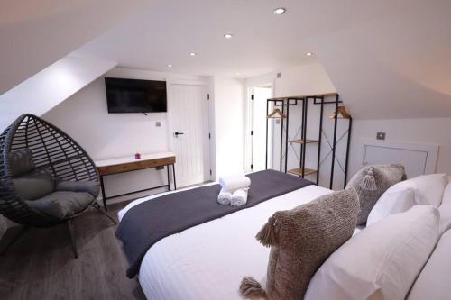 a bedroom with a large bed and a chair at PrimeLocation! Spacious 4BR Apt Market St Watford! in Watford