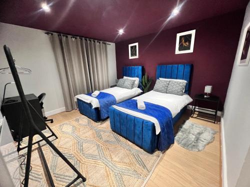 ロンドンにあるLuxury 3 Bed flat close to many attractionsのベッド2台、テレビ、三脚が備わる客室です。