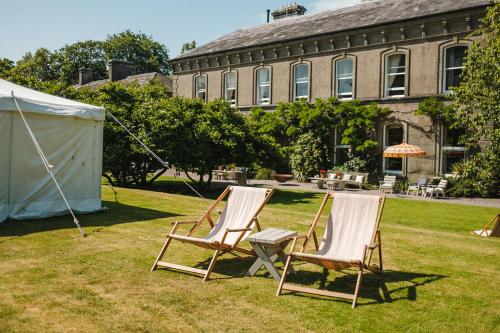 zwei Stühle im Gras vor einem Gebäude in der Unterkunft Ballyvolane House in Fermoy