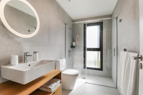 uma casa de banho com um lavatório, um WC e um espelho. em Agaete 3BR Tropical Views em Agaete