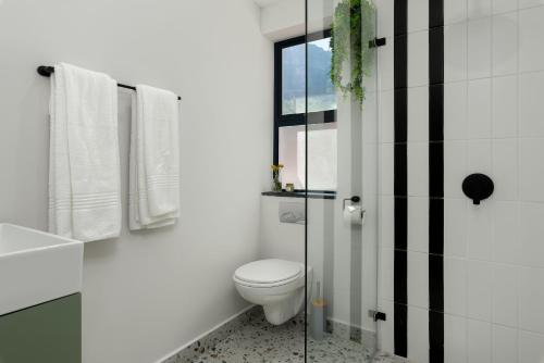 a white bathroom with a toilet and a window at Neighbourgood 1st Crescent in Cape Town