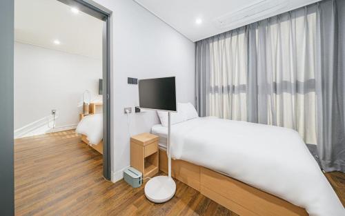una camera d'albergo con letto e TV di Aroomi Hotel Hyupjae a Jeju
