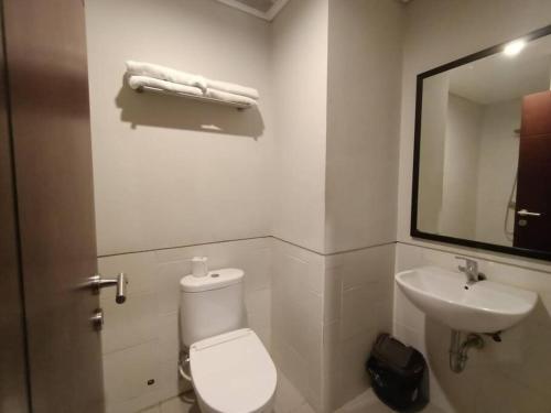 uma casa de banho com um WC, um lavatório e um espelho. em Studio4 in the heart of the city em Denpasar