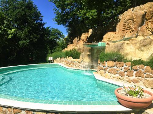 uma piscina num resort com uma parede de pedra em Residence surrounded by greenery with swimming pool in Sorano em Sorano