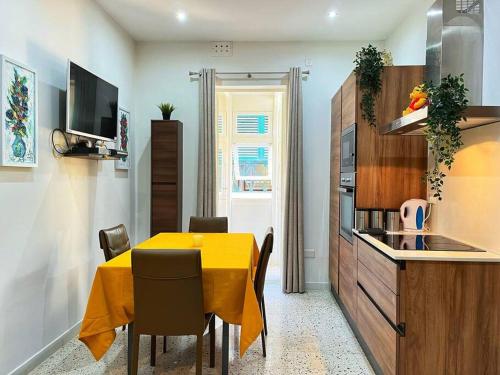 a dining room with a yellow table and a kitchen at Heart of Valletta - Apartment in Valletta