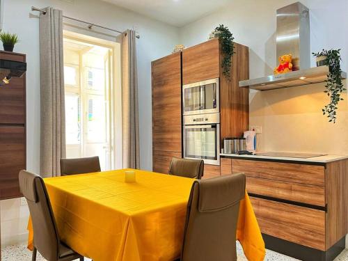 a dining room with a yellow table and a kitchen at Heart of Valletta - Apartment in Valletta