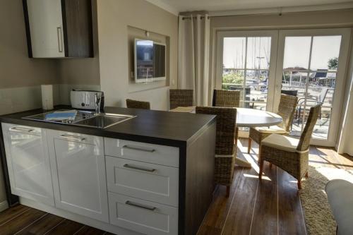 a kitchen with a sink and a table with chairs at HafenResidenz Fehmarn in Lemkenhafen auf Fehmarn