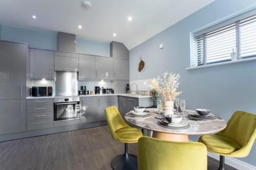 a kitchen with a table and yellow chairs at Elliot Oliver - Luxurious Two Bedroom Apartment in The Docks in Gloucester
