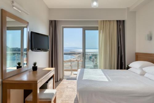 a hotel room with a bed and a desk with a television at Almira Hotel in Arkoudi