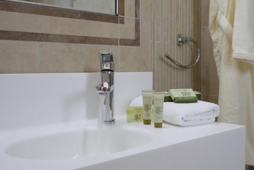 a bathroom with a sink with towels and a faucet at Almira Hotel in Arkoudi