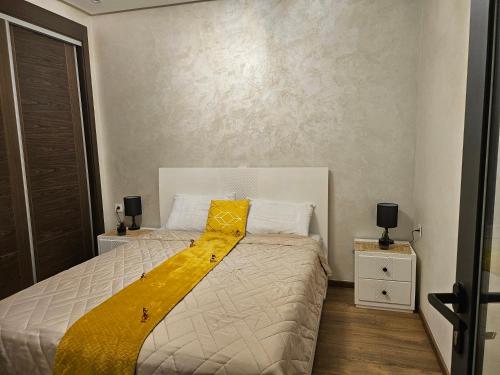 een slaapkamer met een bed met een gele deken erop bij Belle Apparemment à agadie bay in Agadir
