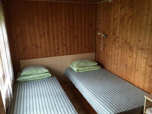 two twin beds in a room with wooden walls at Paju Holiday Home in Otepää