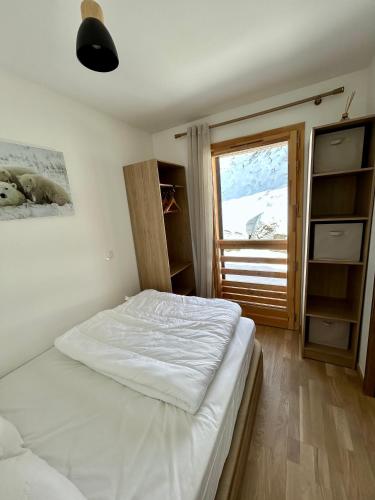 1 dormitorio con cama blanca y ventana en Appartement Valmeinier centre - Le Céleste, en Valmeinier